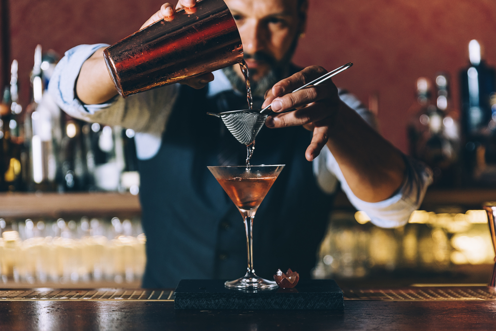 bartender pouring alcohol into martini glass