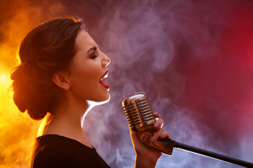 woman singing into chrome microphone