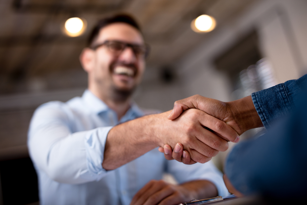 two smiling business people shake hands