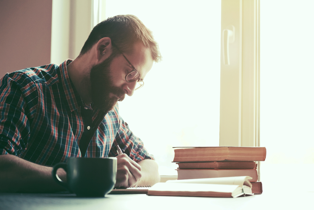 bearded man writing at table