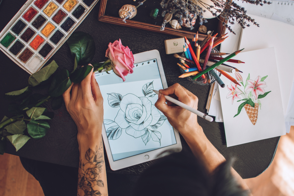 Person with tattoos creating digital art of a flower