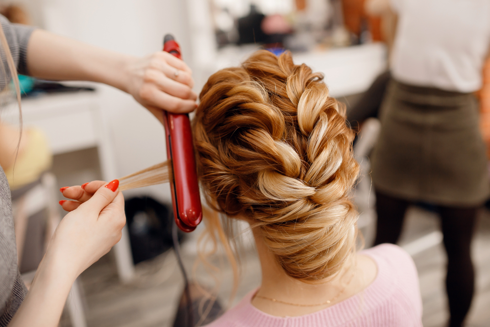 woman creating elaborate hairstyle on client