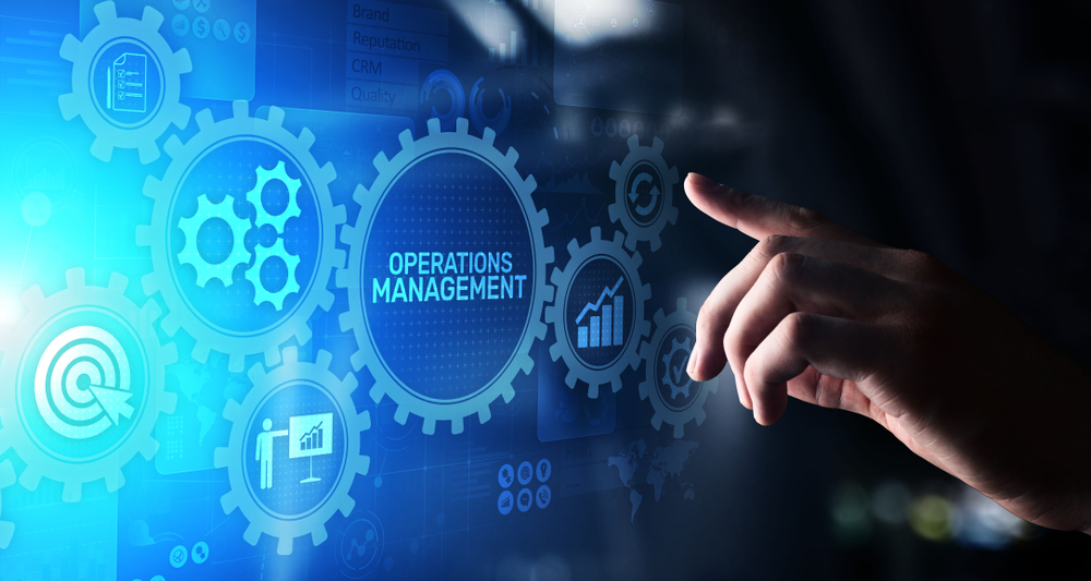hand pointing on a screen with gear icons and the word ‘operations management’